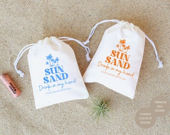 May include: Two white drawstring bags with the text "SUN SAND Drink in my hand" and palm tree graphics. One bag has blue text and the other has orange text.