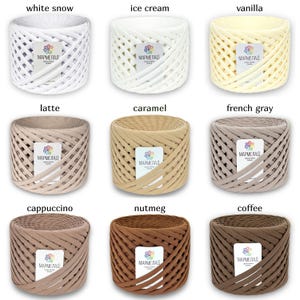 May include: Nine spools of yarn in various shades of brown, beige, and white. The yarn is woven in a basket weave pattern. The spools are labeled with the words "MARMELAD" and the color name, such as "white snow", "ice cream", "vanilla", "latte", "caramel", "french gray", "cappuccino", "nutmeg", and "coffee".