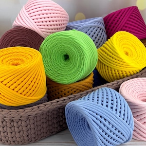 以下が含まれることがあります： ピンク、グリーン、イエロー、ブルー、レッドなど、さまざまな色合いのカラフルな糸玉がバスケットに入っています。糸は装飾的なパターンで配置されており、クラフトプロジェクトの準備ができています。