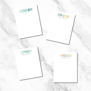 May include: Four white notepad sets with different city area codes and locations printed on them. The area codes are 33040, 29401, 27959, and 99240. The locations are Key West, FL, Charleston, SC, Nags Head, NC, and Palm Springs, CA.