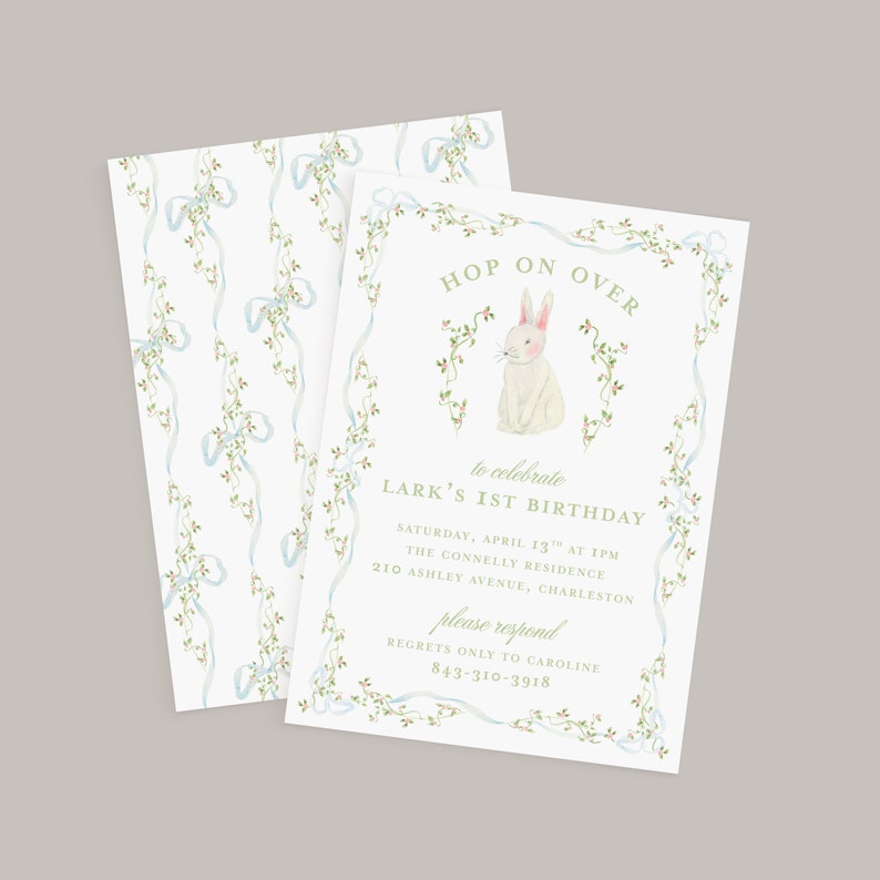 May include: A white bunny with pink ears and nose sits in a wreath of green vines with white flowers. The text "HOP ON OVER" is at the top of the invitation and "to celebrate LARK'S 1ST BIRTHDAY" is below the bunny. The invitation details the date, time, location, and contact information for RSVP.