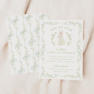 May include: A white bunny with pink ears and nose sits in a green vine wreath with blue ribbons. The text "Hop On Over" is above the bunny and "to celebrate Lark's 1st Birthday" is below the bunny. The invitation includes the date, time, location, and contact information for RSVP.
