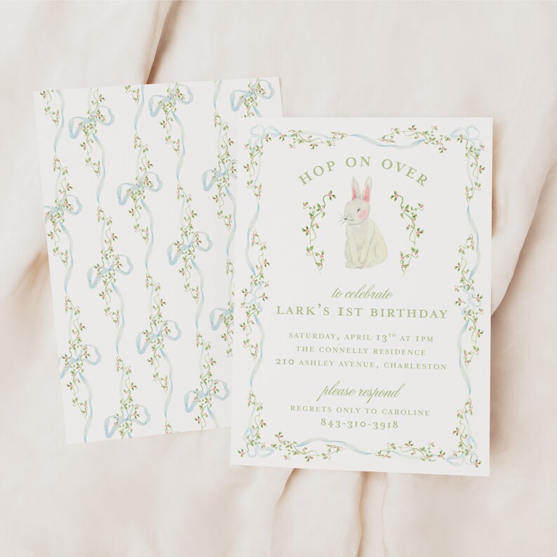 May include: A white bunny with pink ears and nose sits in a green vine wreath with blue ribbons. The text "Hop On Over" is above the bunny and "to celebrate Lark's 1st Birthday" is below the bunny. The invitation includes the date, time, location, and contact information for RSVP.