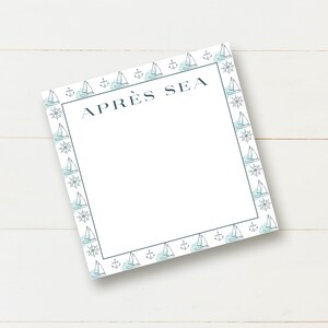 May include: A white notepad with a blue and white border featuring sailboats and anchors. The notepad has the text "APRÈS SEA" at the top.