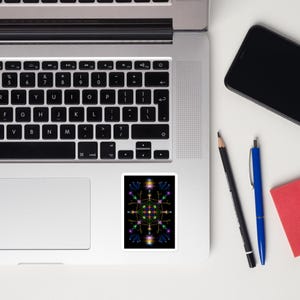 Könnte beinhalten: Ein Aufkleber mit einem farbenfrohen geometrischen Design auf schwarzem Hintergrund. Das Design zeigt ein zentrales Quadrat mit vier nach außen gerichteten Punkten, die eine sternförmige Form bilden. Die Punkte sind mit kleinen, bunten Kreisen und Linien verziert.