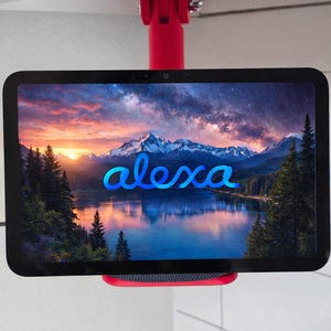 Op de afbeelding: Een rode plafondbevestiging houdt een zwarte tablet vast met een meer- en berglandschap met het woord "alexa" in blauwe letters. De bevestiging is bevestigd aan een wit plafond.