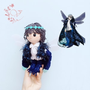 Peut inclure: Un jouet en peluche crocheté avec des ailes bleues et blanches, portant un bandeau bleu et une veste bleue et blanche. Le jouet a un visage bleu et blanc avec des yeux noirs et une bouche noire.