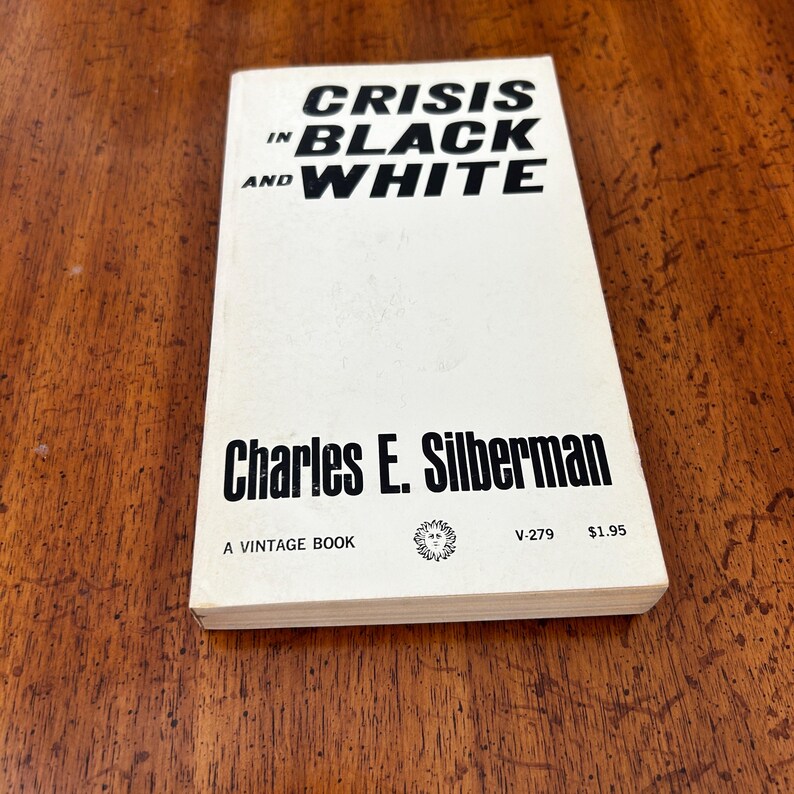 May include: A paperback book titled Crisis in Black and White by Charles E. Silberman. The cover is white with bold black text. It features the text A VINTAGE BOOK, a small sun-like logo, the code V-279, and the price $1.95 at the bottom.
