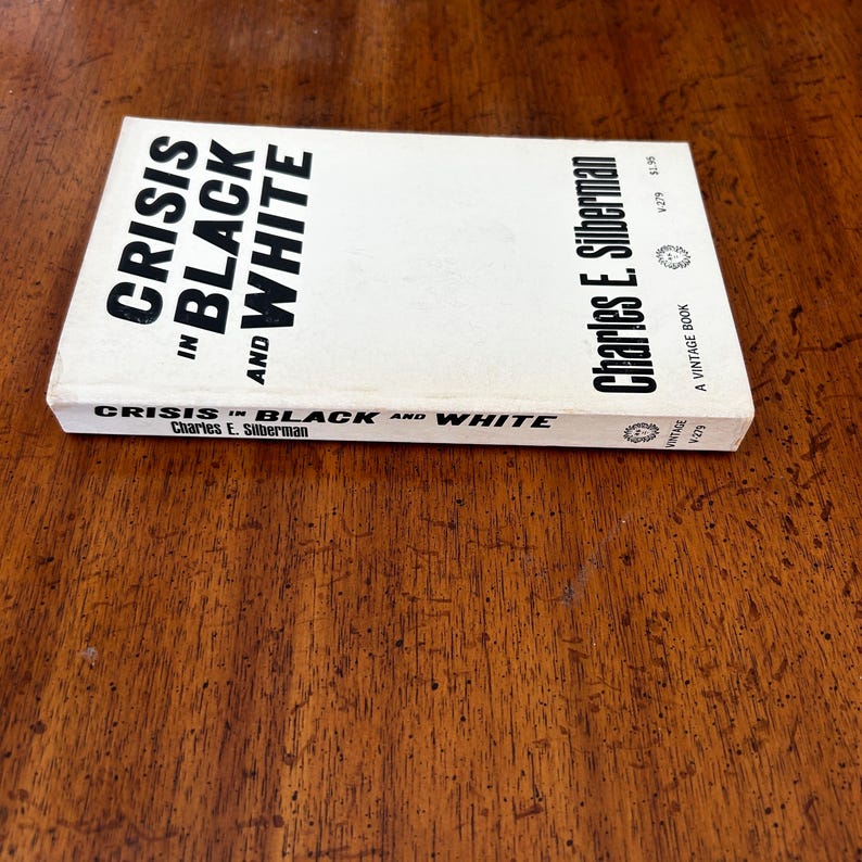 May include: A paperback book titled Crisis in Black and White by Charles E. Silberman. The cover is white with bold black text. The spine also displays the title and author name in black text against a white background, including the Vintage logo.