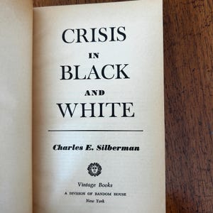 May include: The title page of the book Crisis in Black and White by Charles E. Silberman, published by Vintage Books, a division of Random House, New York. The text is printed in black ink on a cream-colored page with a small sun icon logo.