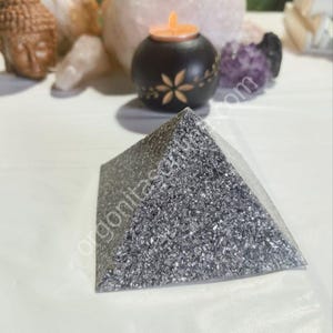 May include: A silver pyramid shaped crystal with a sparkly, textured surface.