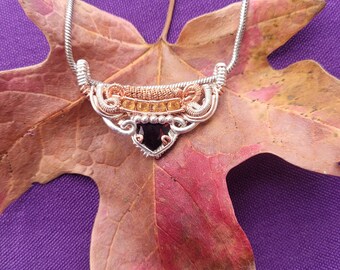 May include: A silver chain necklace with a copper and silver wire wrapped pendant featuring a dark gemstone and amber-colored beads.