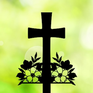 May include: A black silhouette of a cross with floral accents. The cross is set against a blurred green background.