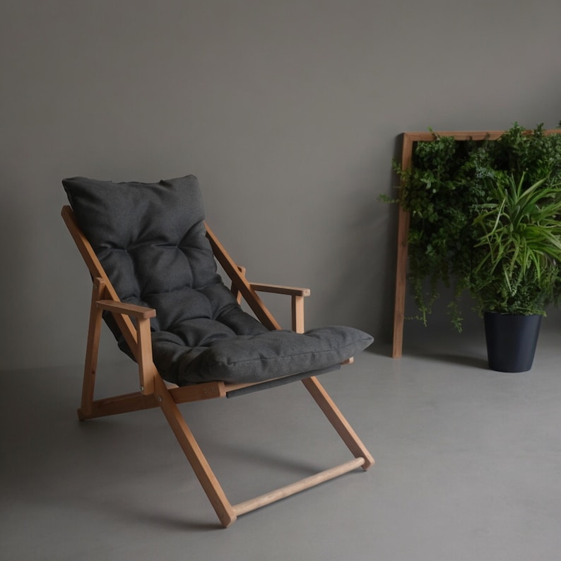 May include: A dark grey folding chair with a wooden frame. The chair has a padded seat and back.