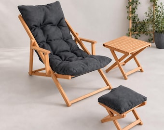 May include: A folding wooden lounge chair with a tufted dark gray cushion, a matching small folding wooden stool with a dark gray cushion, and a small square folding wooden side table with a slatted top surface, all featuring a light wood finish.