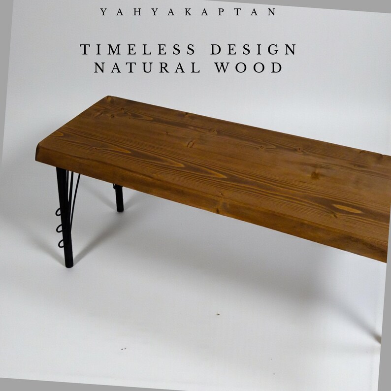 K&ouml;nnte beinhalten: Eine rechteckige Bank mit einer naturfarbenen, braunen Holzmaserung und schwarzen Metallbeinen mit dekorativen kreisf&ouml;rmigen Akzenten. Der Text YAHYA KAPTAN, TIMELESS DESIGN und NATURAL WOOD steht in schwarzen Buchstaben dar&uuml;ber.