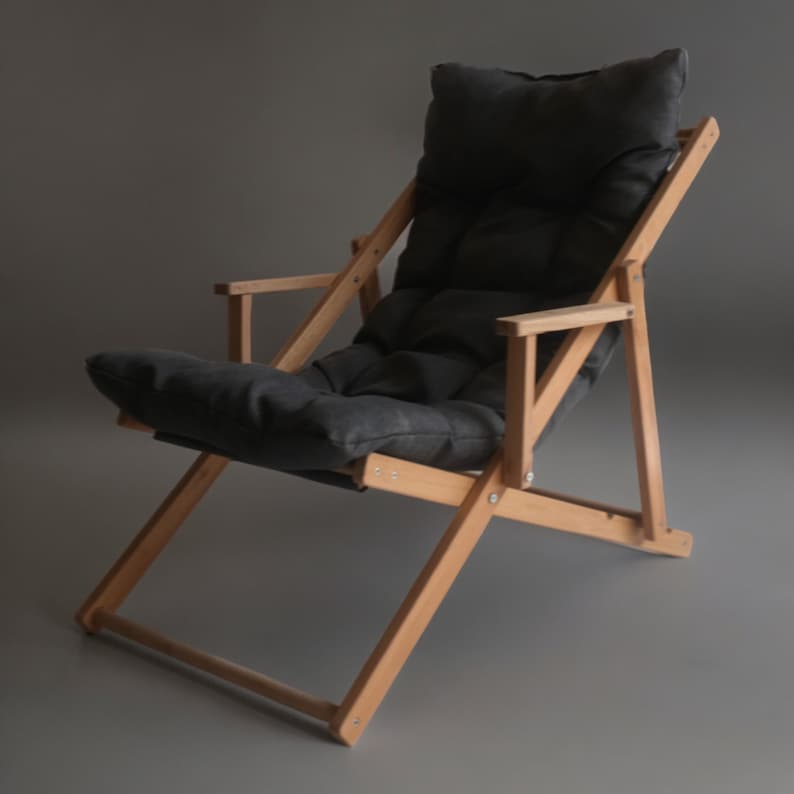 May include: A wooden folding chair with a dark grey fabric cushion. The chair is made of natural wood and has a simple, classic design.