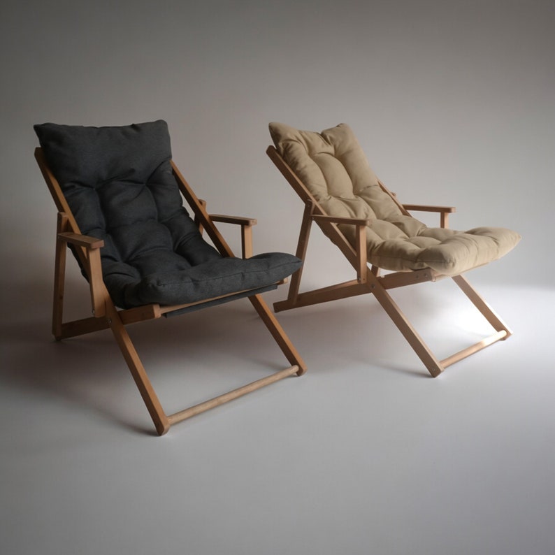 May include: Two wooden folding chairs with fabric cushions. One chair has a dark gray cushion and the other has a light beige cushion.
