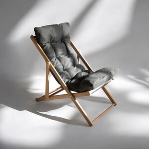 May include: A wooden folding chair with a gray padded seat. The chair is made of natural wood and has a simple design.
