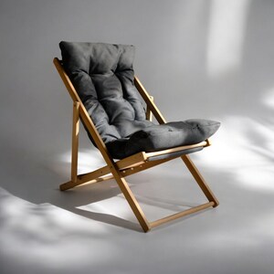 May include: A wooden folding chair with a gray fabric cushion. The chair is made of natural wood and has a simple, modern design.