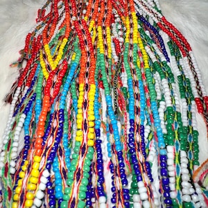 May include: A close-up of a collection of colorful beaded strands, featuring a variety of colors including red, yellow, blue, green, and white. The beads are strung on thin threads and are arranged in a cascading pattern.