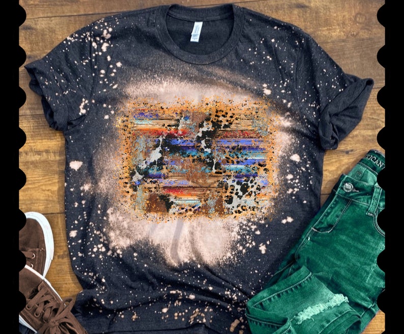 May include: A black t-shirt with a bleach-splattered design featuring a colorful abstract pattern with animal print accents.