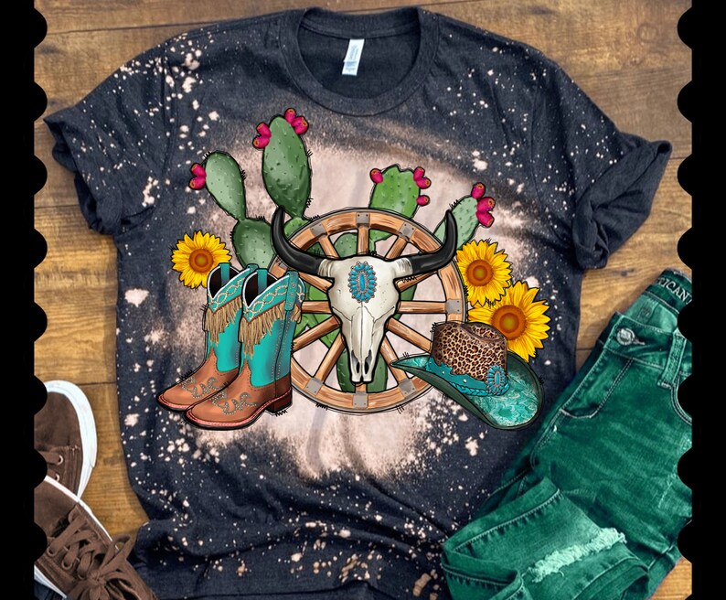 May include: A black t-shirt with a bleached design featuring a wagon wheel, a skull, cowboy boots, and sunflowers. The design is on a black t-shirt with a distressed look.