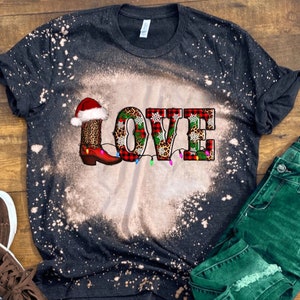 May include: Black bleached t-shirt with a red, green, and white "LOVE" graphic featuring a Christmas boot, snowflakes, and lights.