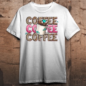 May include: White t-shirt with a graphic of a coffee cup with hearts and the text "COFFEE" repeated three times.