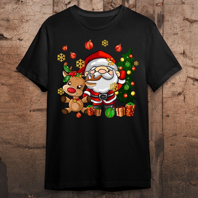 Pode incluir: Uma camiseta preta com uma imagem de desenho animado do Papai Noel e uma rena. O Papai Noel est&aacute; vestindo um terno vermelho com detalhes brancos e uma barba branca. A rena &eacute; marrom com o nariz vermelho. Ambos est&atilde;o em p&eacute; na frente de uma &aacute;rvore de Natal verde com enfeites vermelhos e dourados.