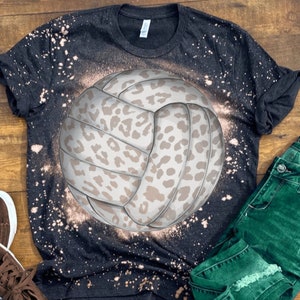 May include: A black t-shirt with a white bleached design of a volleyball with a leopard print pattern.