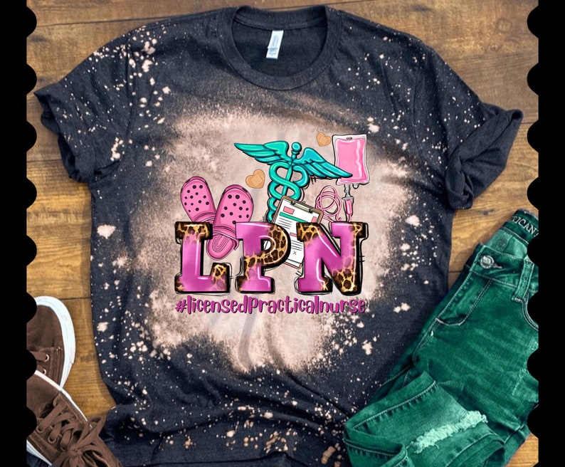 May include: Black t-shirt with a bleach-splattered design featuring a pink and leopard print "LPN" with a medical symbol, a stethoscope, and a pair of pink clogs. The text below reads "#LicensedPracticalNurse".