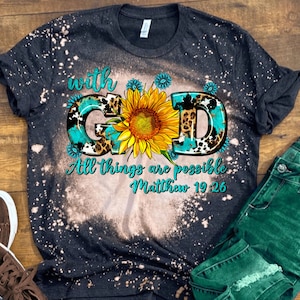 May include: Black bleached t-shirt with a turquoise, leopard print, and sunflower design. The text "with God All things are possible Matthew 19:26" is printed on the shirt.