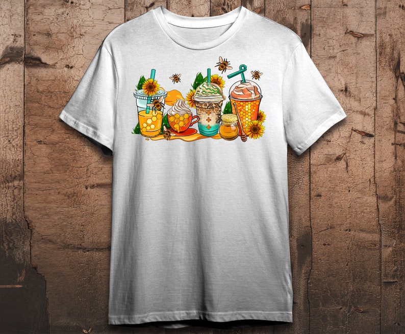 May include: White t-shirt with a graphic of four iced coffee drinks decorated with honeycombs, sunflowers, and bees. The text "Honeycomb" is printed on the shirt.