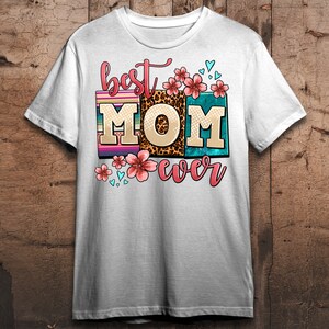 May include: White t-shirt with the text "best MOM ever" in colorful block letters with floral and leopard print accents.