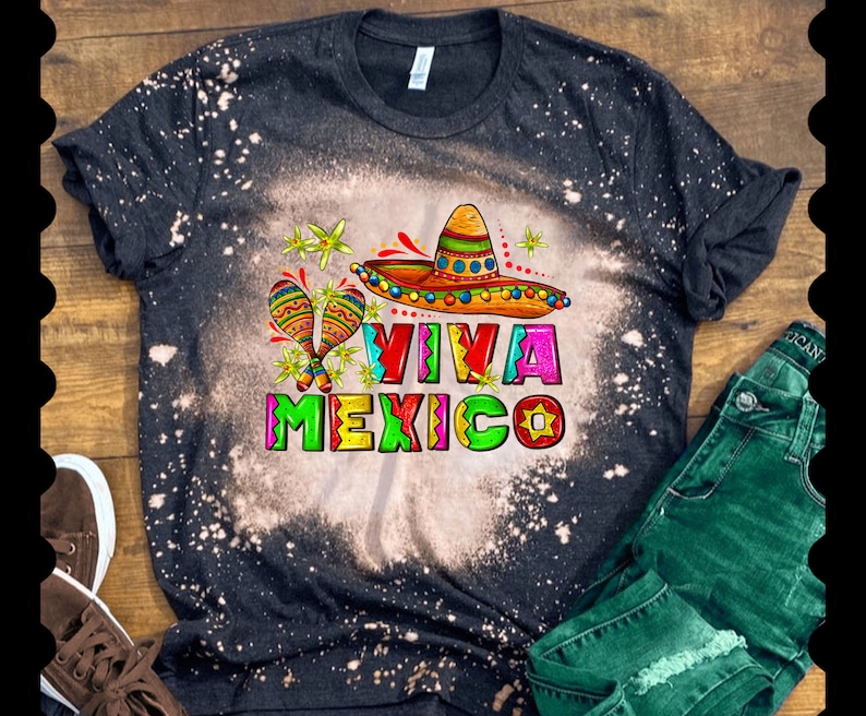 Może przedstawiać: Czarny T-shirt z wzorem rozpryskanym wybielaczem, przedstawiający kolorowy sombrero, marakasy i napis "Viva Mexico".