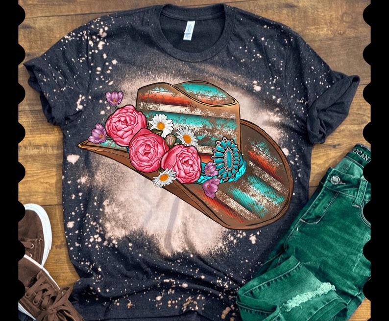 May include: A black t-shirt with a bleached design of a turquoise and brown cowboy hat with pink and white flowers.