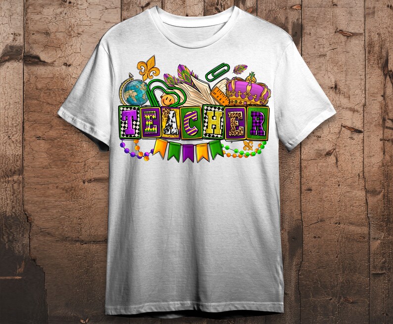 May include: White t-shirt with a colorful design featuring the word "TEACHER" in block letters with Mardi Gras beads and a crown.