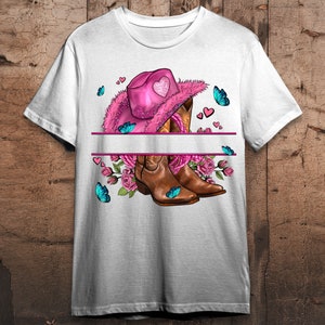 Puede incluir: Camiseta blanca con un sombrero vaquero rosa, botas vaqueras marrones, flores rosas y mariposas azules. El sombrero tiene un dise&ntilde;o de coraz&oacute;n en la parte delantera.