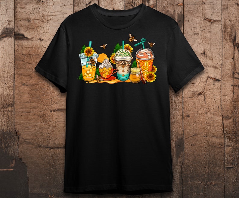 May include: Black t-shirt with a graphic of four iced coffee drinks decorated with honeycombs, bees, and sunflowers.