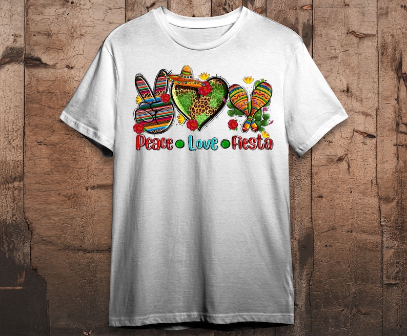 Puede incluir: Camiseta blanca con un gr&aacute;fico de signo de paz, coraz&oacute;n y maracas. El gr&aacute;fico est&aacute; en un estilo mexicano colorido con rojo, amarillo, verde, azul y negro. El texto "Peace Love Fiesta" est&aacute; debajo del gr&aacute;fico.