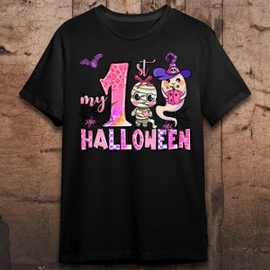 K&ouml;nnte beinhalten: Schwarzes T-Shirt mit einer pinkfarbenen und wei&szlig;en Grafik einer Mumie und eines Geistes. Die Grafik lautet "my 1st Halloween".