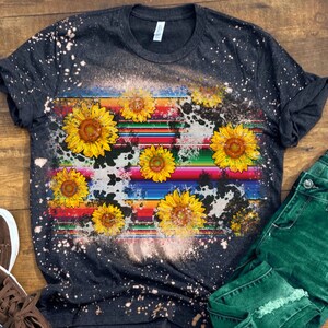 May include: A black t-shirt with a bleach-splattered design featuring a colorful striped pattern and yellow sunflowers.