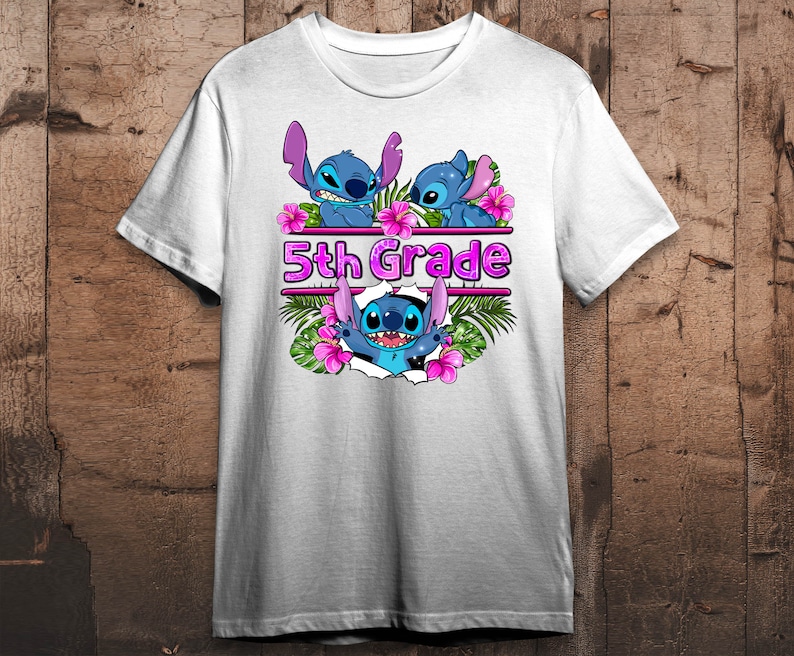 Op de afbeelding: Wit T-shirt met een blauw Stitch-personage ontwerp. Het Stitch-personage draagt een lei en er zijn roze bloemen en palmbladeren omheen. De tekst "5th Grade" is in roze letters op het shirt gedrukt.