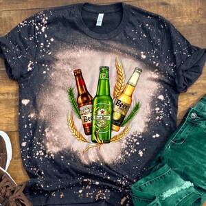 May include: A black t-shirt with a bleach-splattered design featuring three bottles of beer with wheat stalks. The bottles are labeled "Beer" and "Beer Lager".