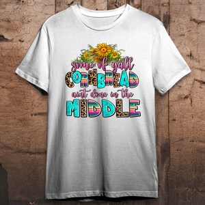 Pode incluir: Camiseta branca com um design gr&aacute;fico que apresenta girass&oacute;is, estampa de leopardo e o texto "some of yall cornbread ain't done in the middle".