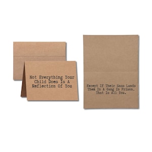 May include: Kraft-colored greeting cards with humorous text. One card is open, displaying the message "Not Everything Your Child Does Is A Reflection Of You." The other card reads "Except If Their Sass Lands Them In A Gang In Prison, That Is All You."