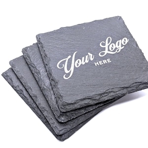 May include: Set of four gray slate coasters with a white inscription that reads "Your Logo Here".