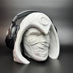 May include: White 3D printed bust of a masked figure wearing a hooded cloak. The figure is wearing headphones.