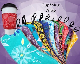 May include: A collection of fabric cup and mug wraps featuring various colorful patterns including sunflowers, paisley, and floral designs. Each wrap includes a black elastic loop and is shown alongside a white cup with a red patterned wrap.